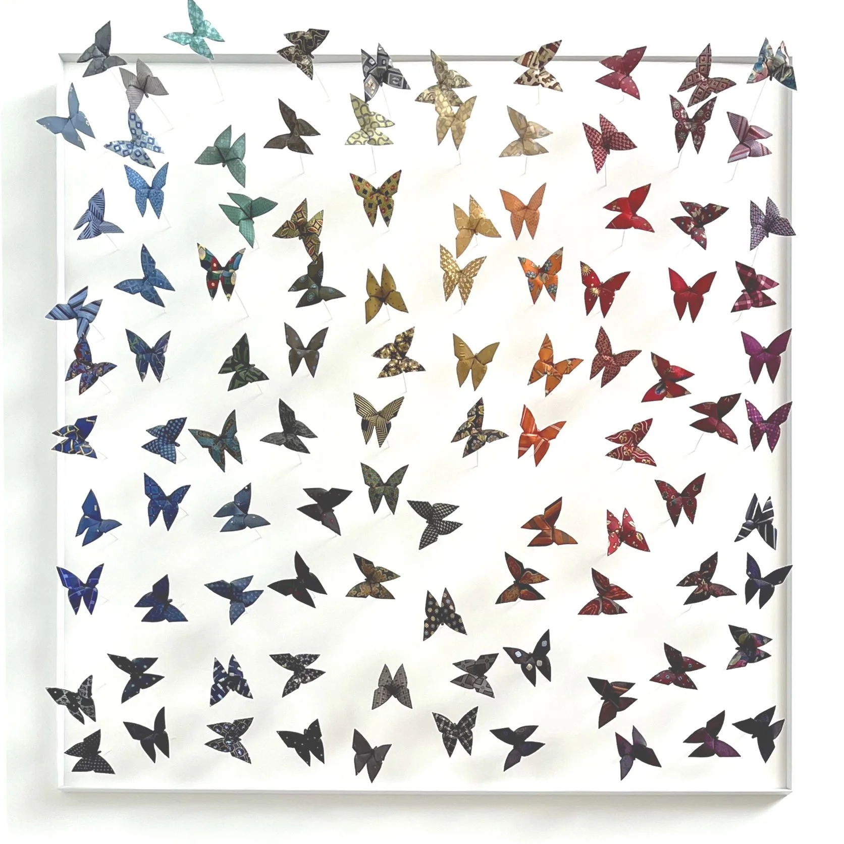 Une installation d'origamis en forme de papillons colorés suspendus verticalement, disposés en plusieurs rangées sur un fond blanc.