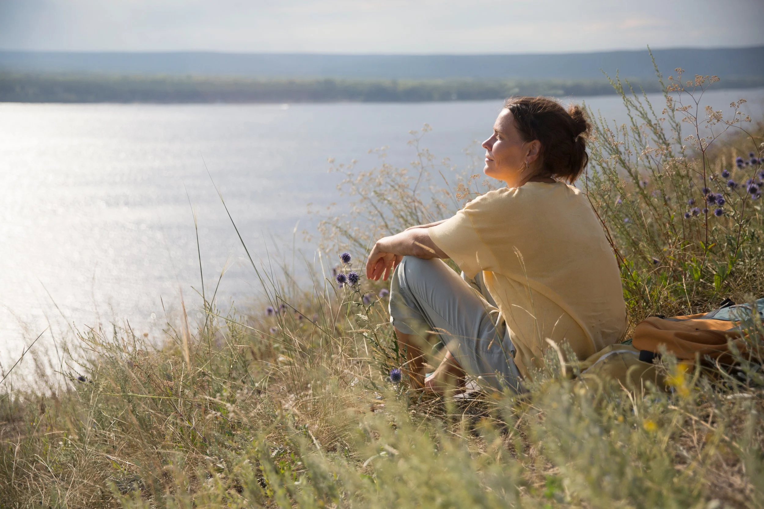 Woman sitting in the grass looking at the lake