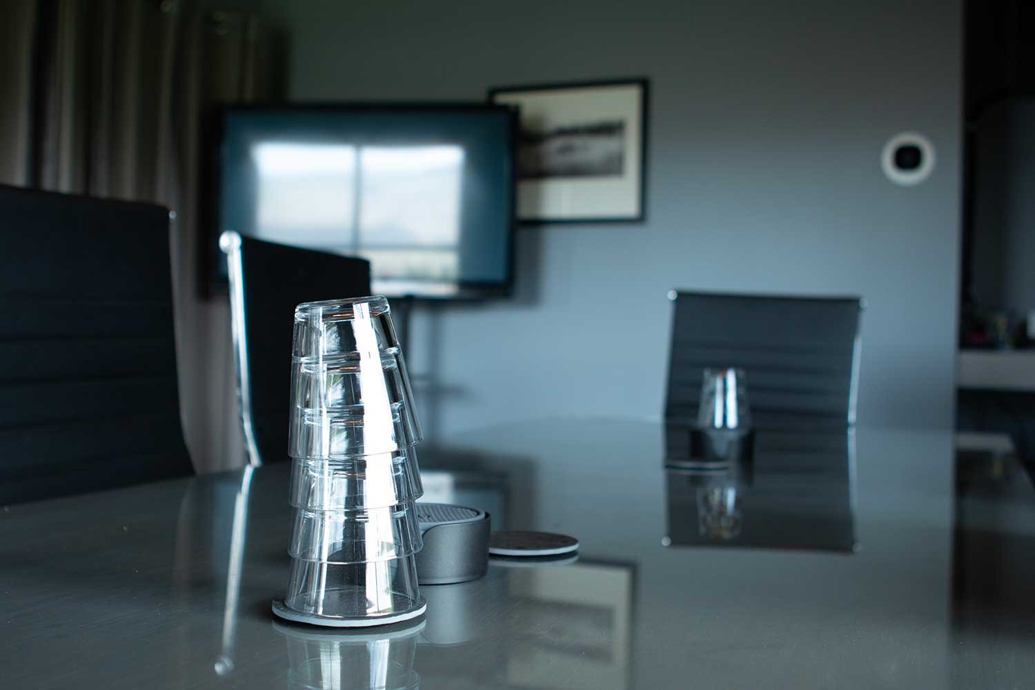 Fairview Mountain Golf Club meeting room with stacked upside-down glasses on a table, chairs, a television, and framed pictures on the wall.
