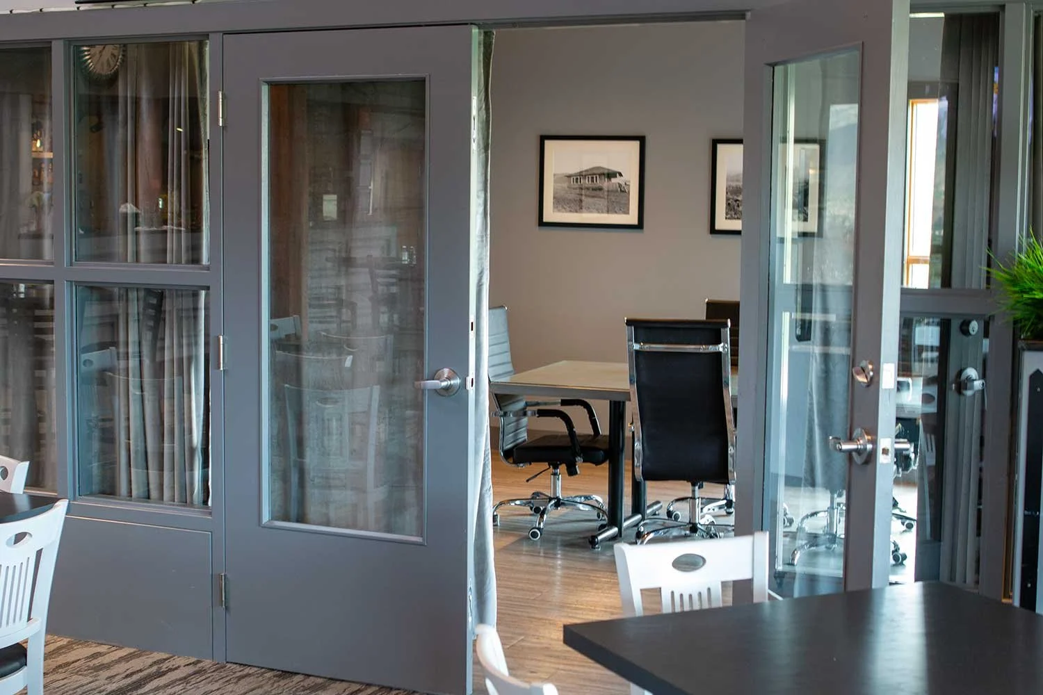 View through glass doors into the Fairview Mountain Golf Club meeting room with chairs, a large table, and framed artwork on the walls.