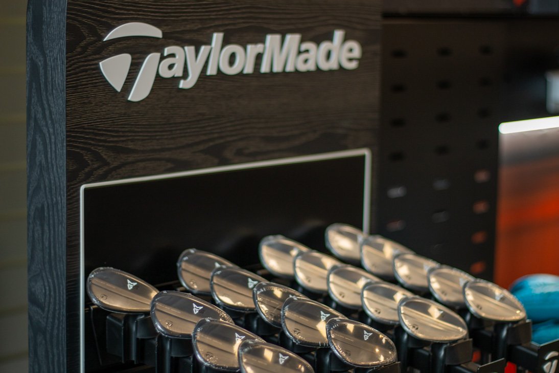 Golf clubs with shiny metal heads displayed in a TaylorMade display rach in the Fairview Mountain Golf Club pro shop.