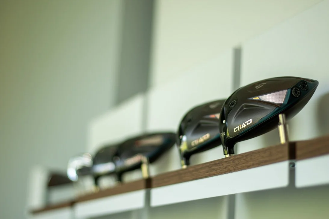 Golf clubs displayed in the Fairview Mountain Golf Club fitting bay on a wooden shelf.