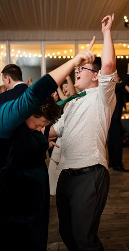 People dancing at an indoor party with string lights in the background.