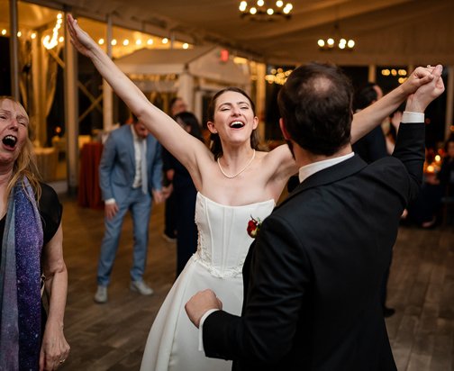 A woman in a wedding dress celebrating with a man in a suit at a wedding reception.