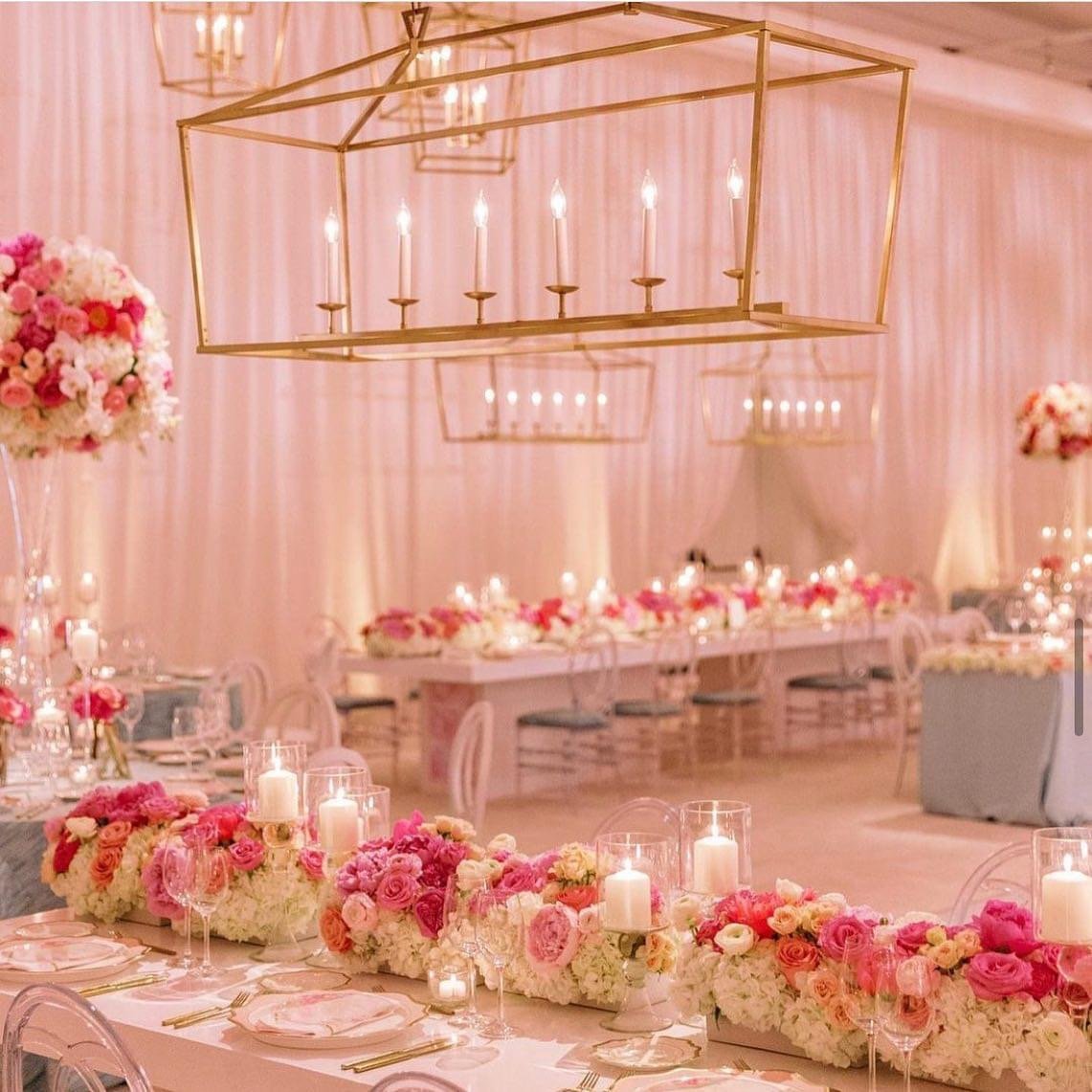 Elegant event space decorated with pink and white flowers, floating candles, and gold chandeliers, set up for a celebration
