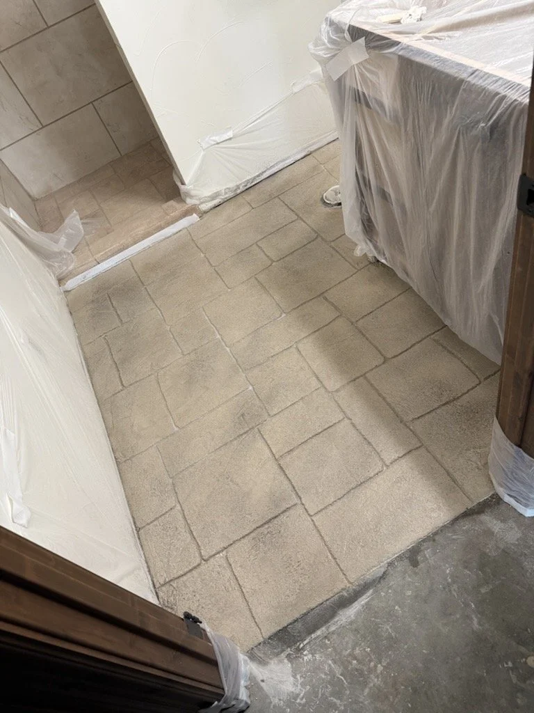A room with a new beige tile floor, partially covered with plastic sheeting, indicating ongoing renovation or construction work.