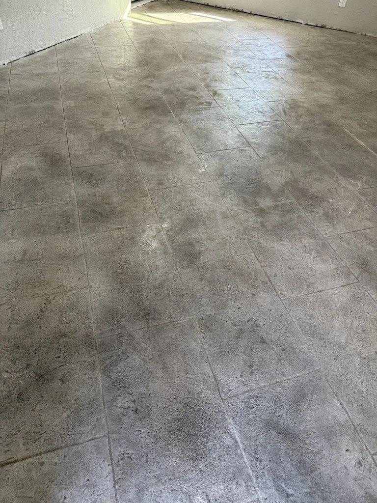 Concrete tile flooring in a room with a small opening near the wall, allowing natural light to enter.