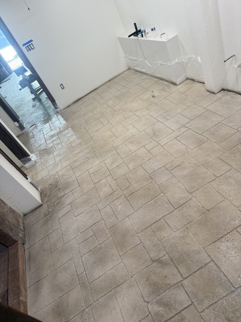 Room with newly installed beige tile flooring, some areas still drying, and a corner with a small countertop with a sink and a faucet.