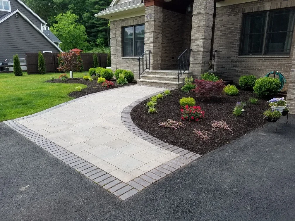 Colorful planting bed bordering a paver walkway. - Green Nature Landscape Design