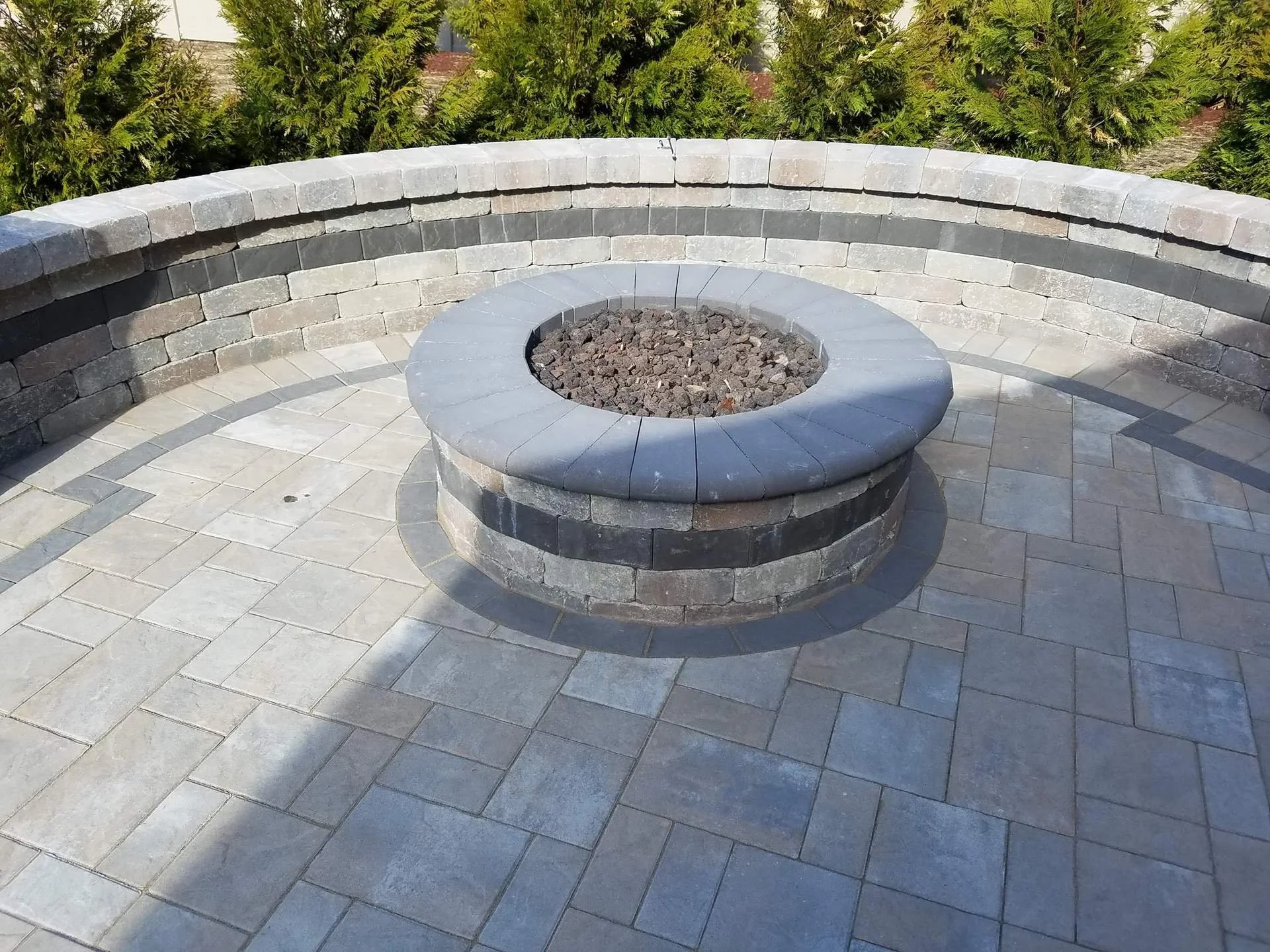 A seating wall surrounding a fire pit area in an outdoor living space.