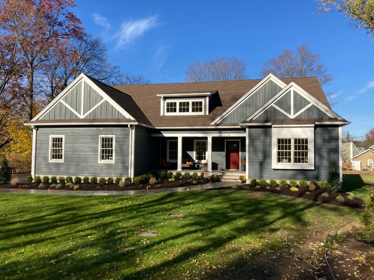 Newly landscaped front yard with foundation plantings, fresh mulch beds, and a paver entry walk at a craftsman-style home. — Green Nature Landscape Design