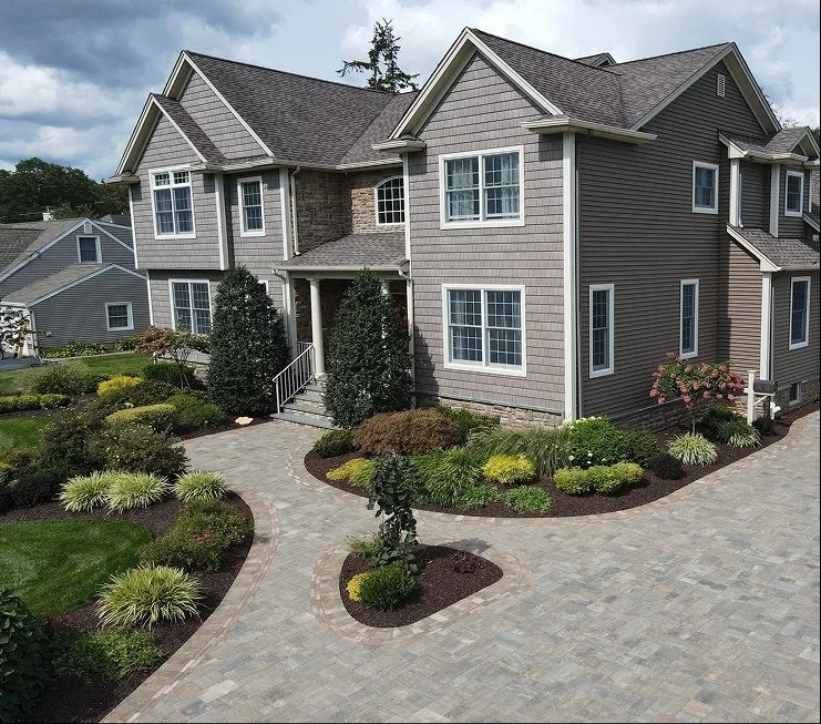 Front entry paver walkway with curved landscape beds and layered shrub plantings at a two-story home — Green Nature Landscape Design