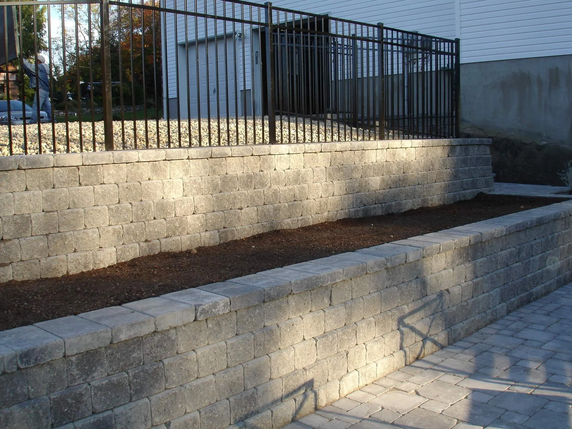 A retaining wall with coordinating hardscape materials along a paver walkway.