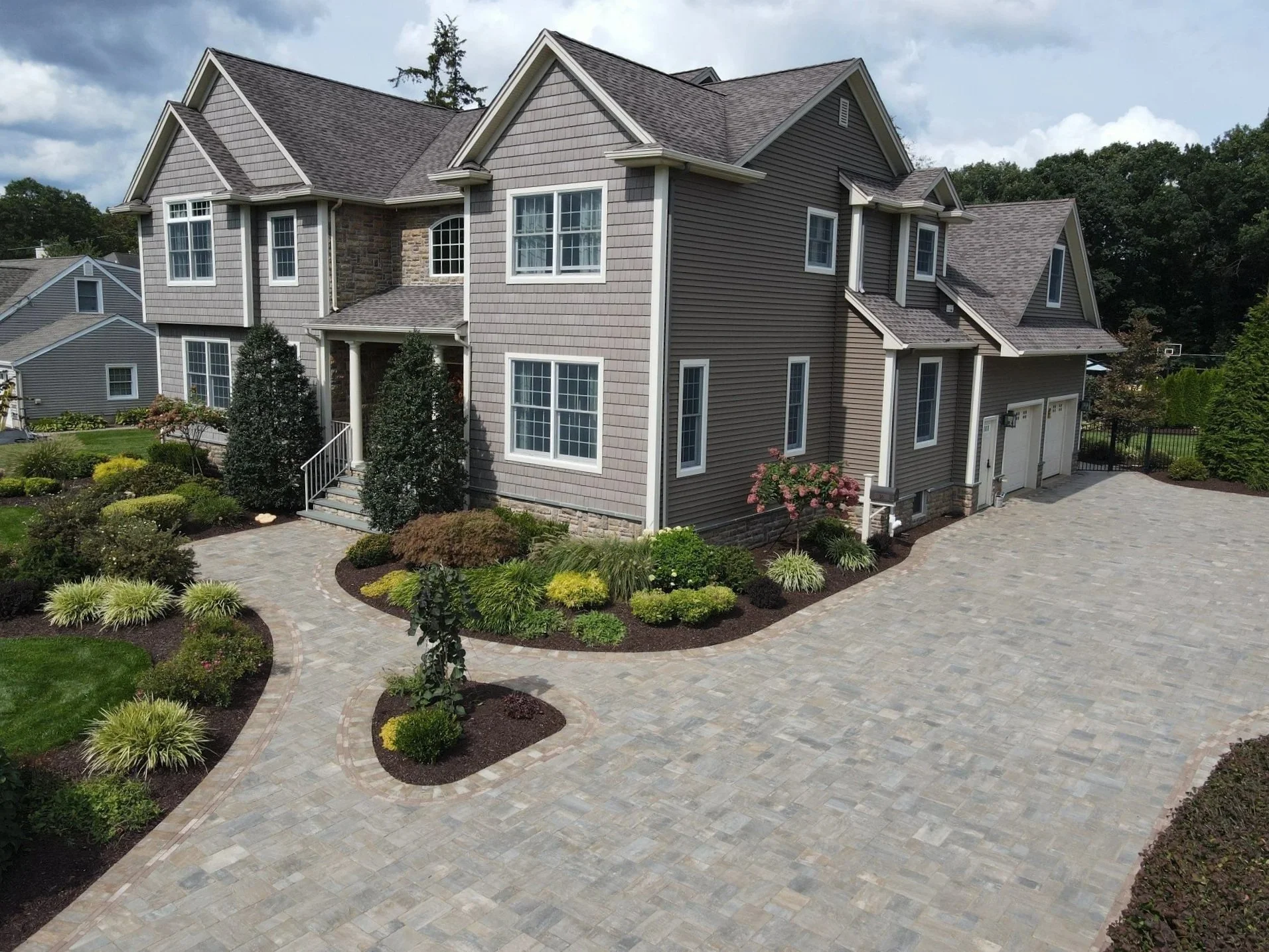 Elegant plantings with shrubs and greenery along a paver walkway.  - Green Nature Landscape Design
