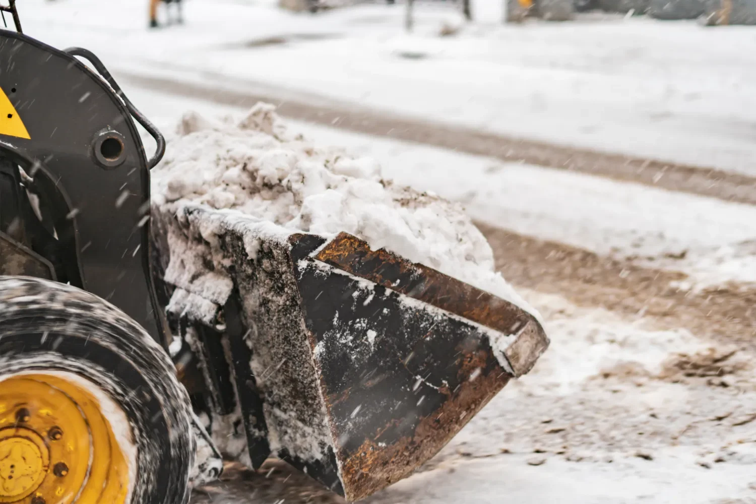 Heavy-duty plow blade clearing snow and ice from a commercial parking area during winter