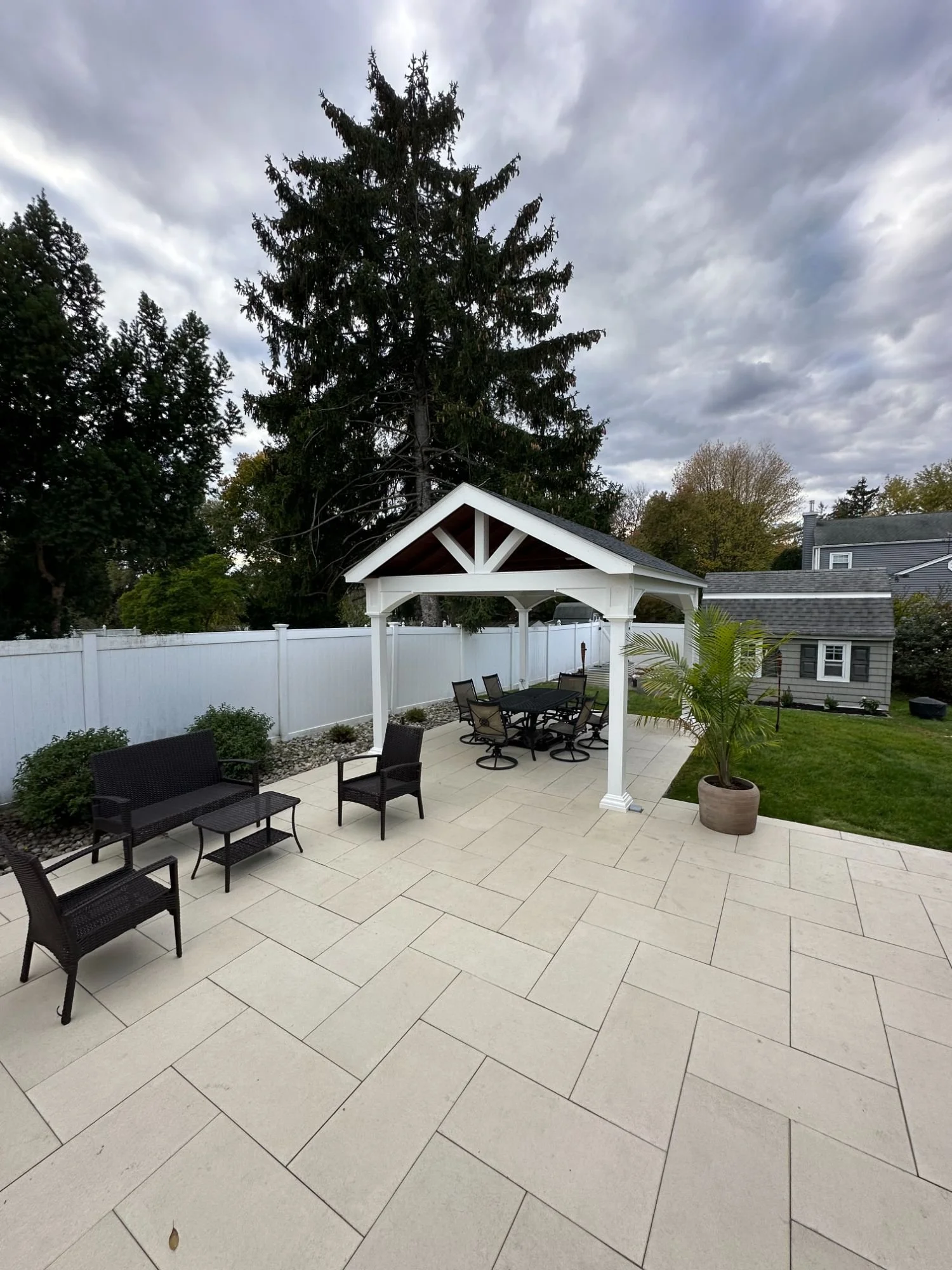 White pergola over a paver patio with outdoor lounge furniture in a residential backyard — Green Nature Landscape Design