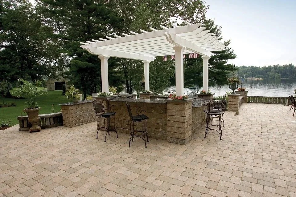 Outdoor pergola over a paver patio with bar seating and an outdoor kitchen — Green Nature Landscape Design