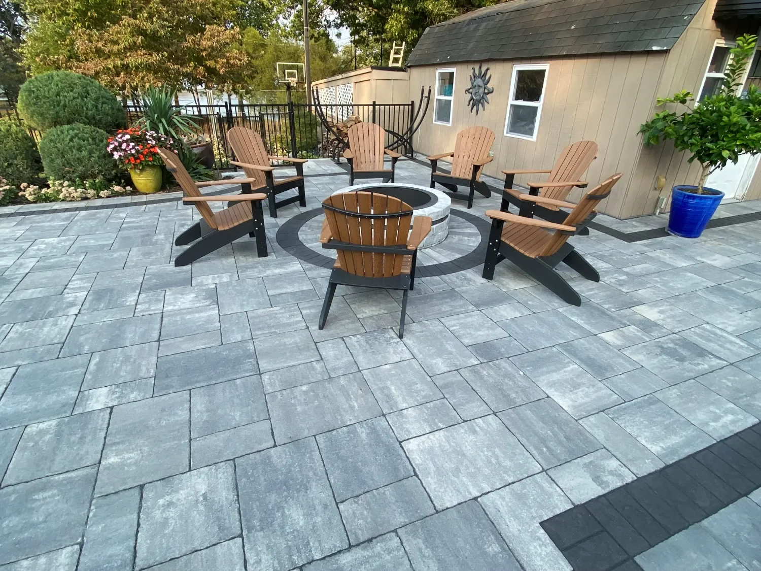 Circular paver patio with built-in fire pit surrounded by Adirondack chairs — Green Nature Landscape Design