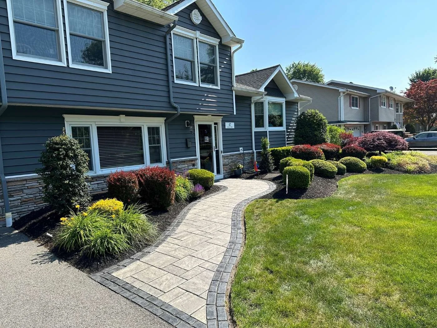 Elegant paver walkway installation surrounded by landscape design and plantings. — Green Nature Landscape Design