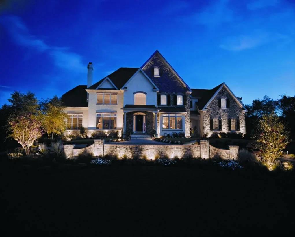 Landscape lighting illuminating home exterior. - Green Nature Landscape Design