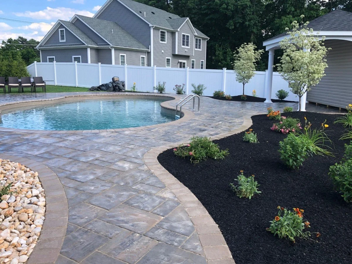 A stunning poolscape with a sparkling swimming pool and resort-style backyard design.  - Green Nature Landscape Design