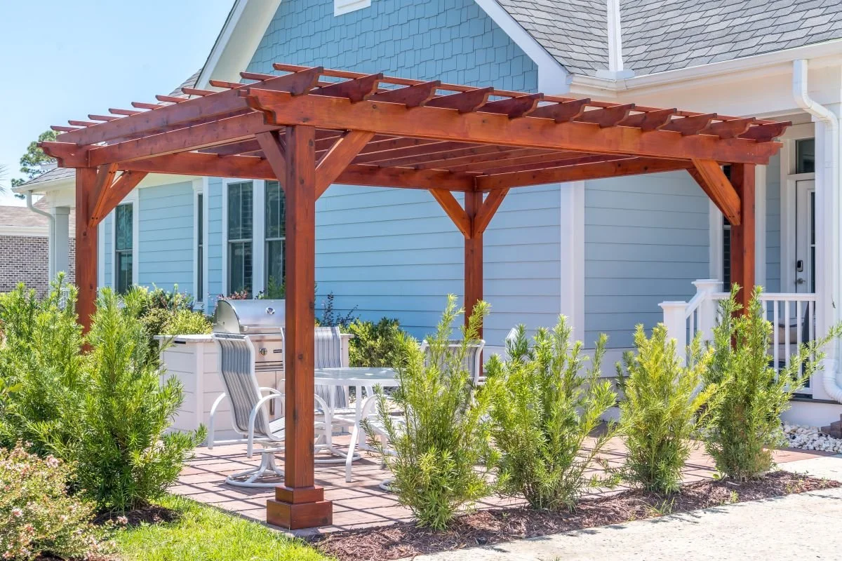 A pergola paired with lush plantings and a paver walkway.
