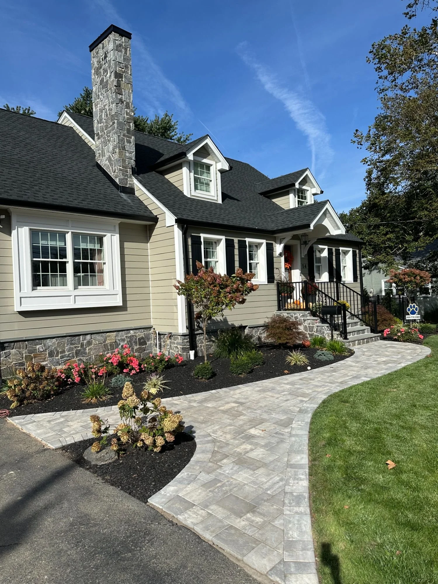 Curved paver walkway through a front yard landscape bed with colorful seasonal plantings — Green Nature Landscape Design