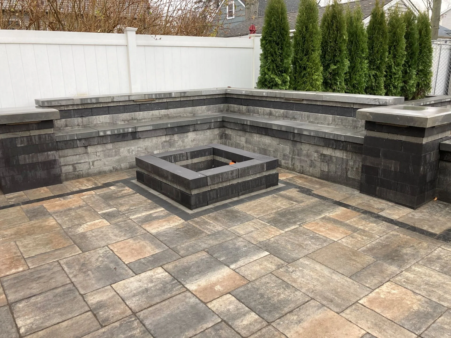 A backyard fire pit installation with seating walls. - Green Nature Landscape Design