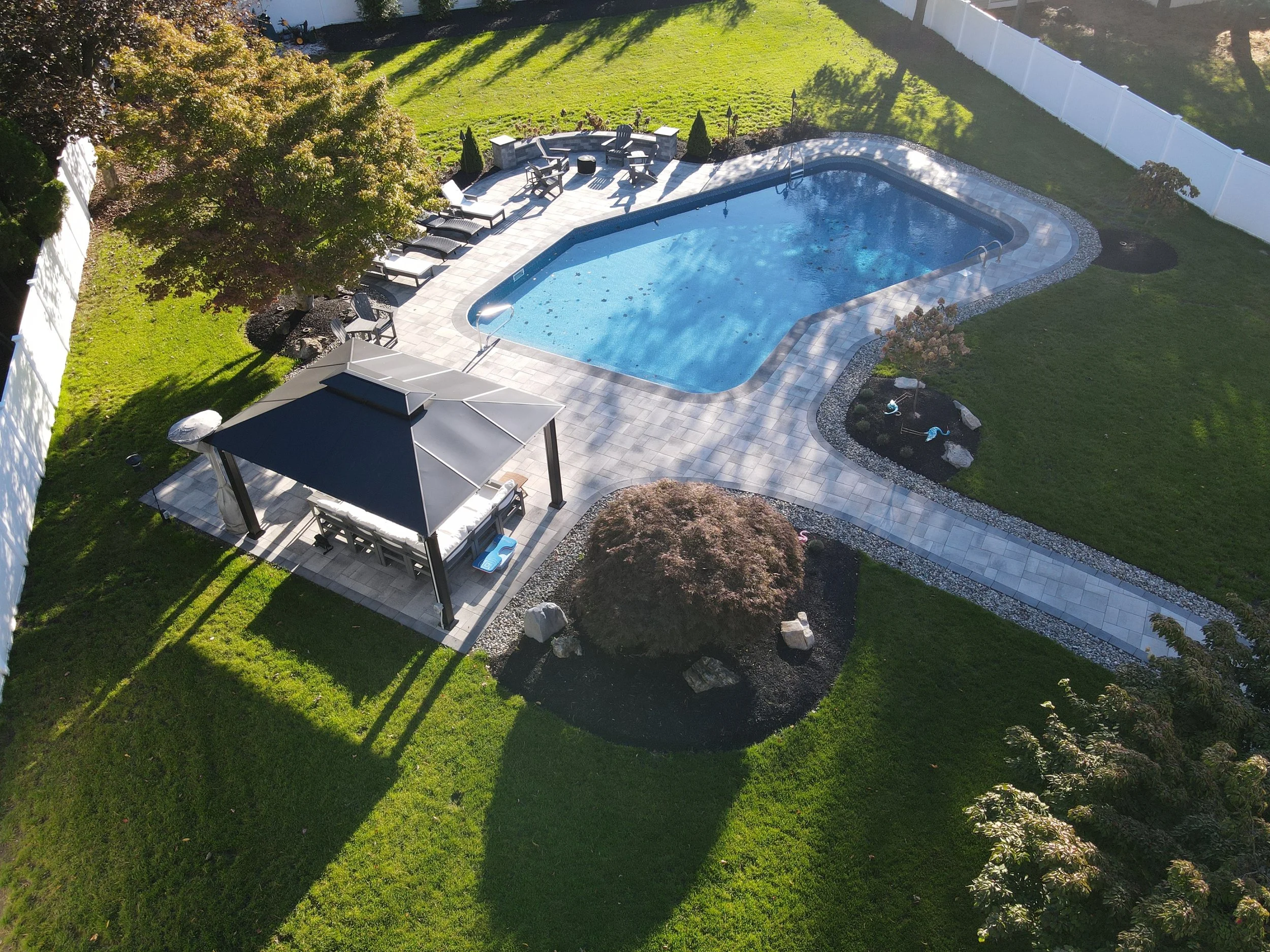 A luxury swimming pool landscaping project with fire pit seating area in Oakland, NJ