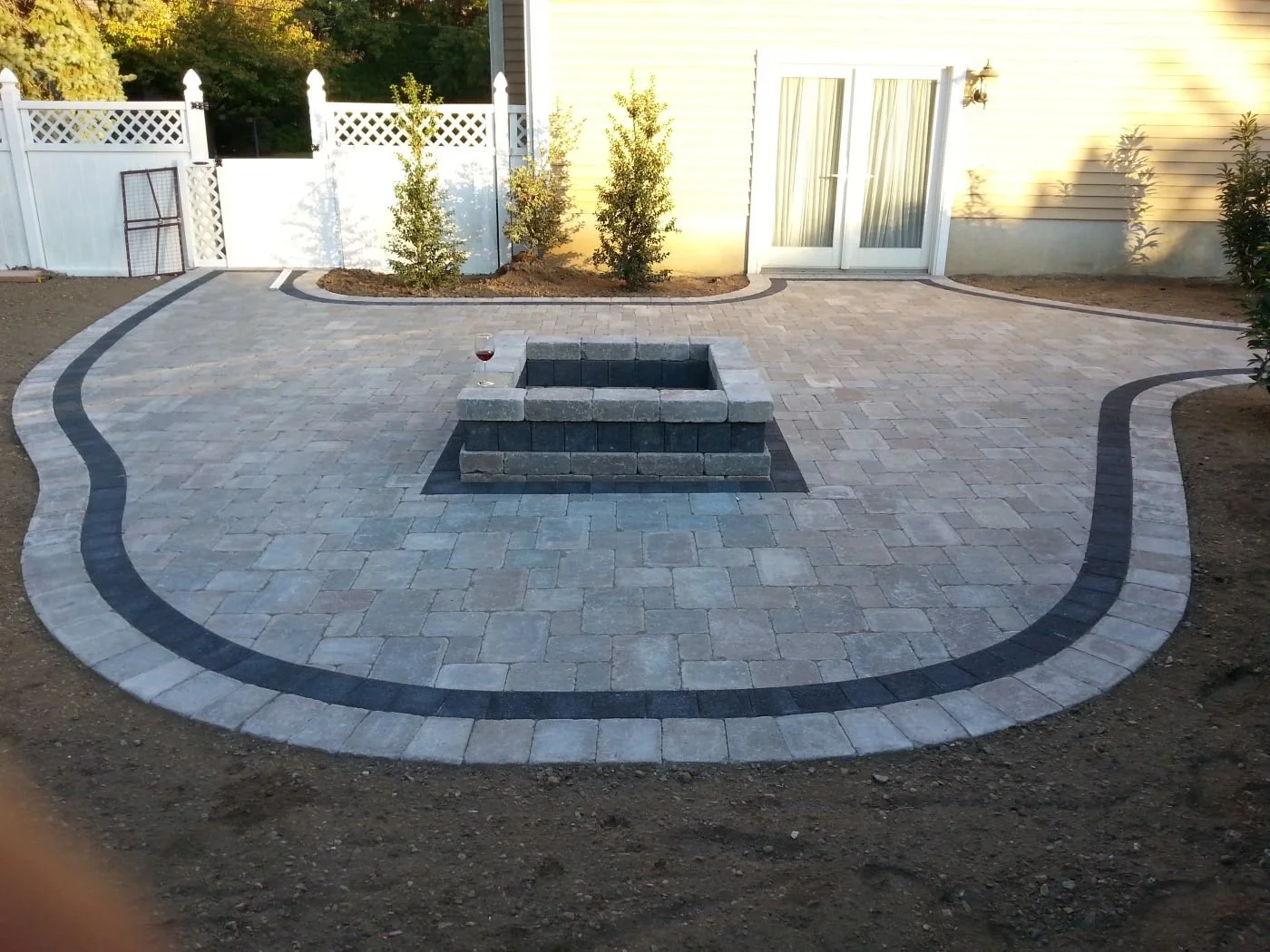 A fire pit and outdoor kitchen creating a complete backyard entertaining space. - Green Nature Landscape Design