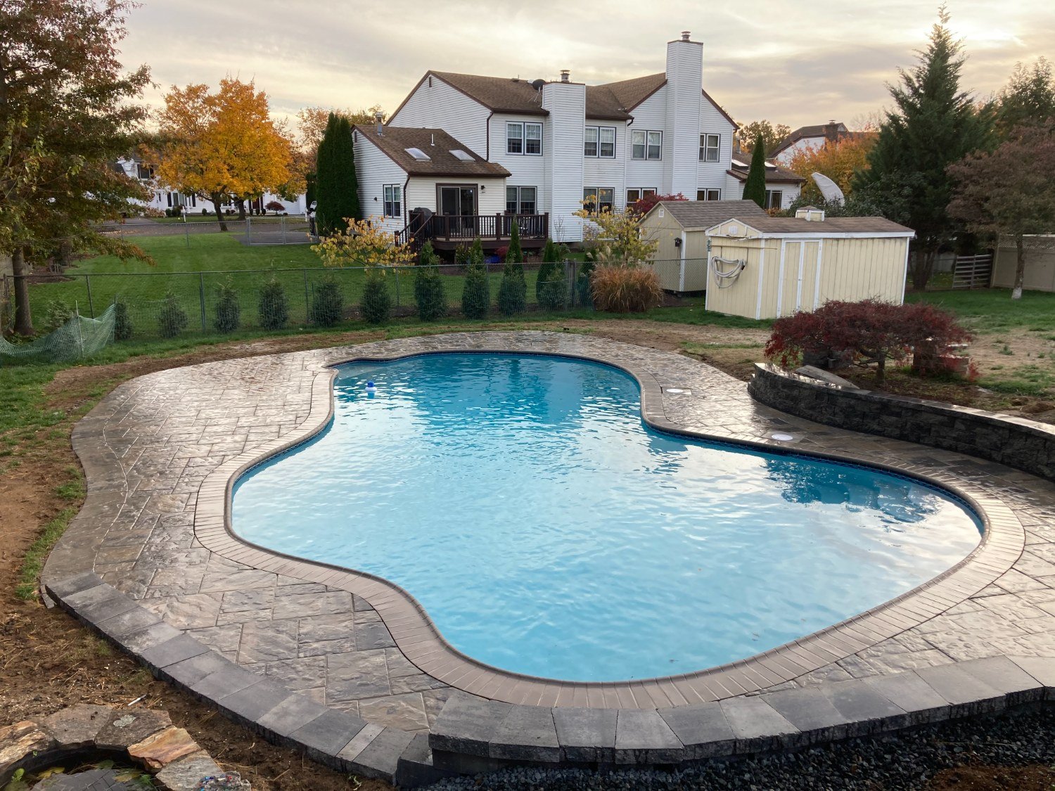 Custom swimming pool landscaping with paver patio and surrounding plantings in Mountain Lakes, NJ
