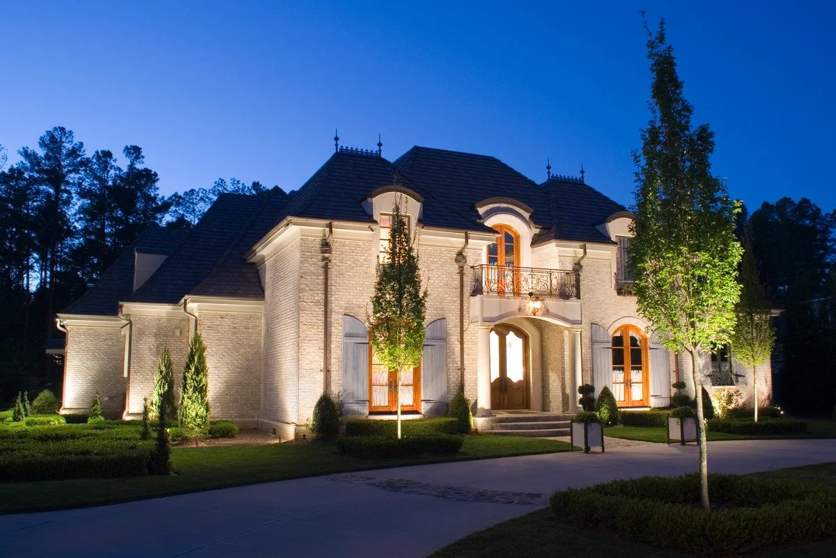 Warm landscape lighting casting a soft glow over home exterior. - Green Nature Landscape Design
