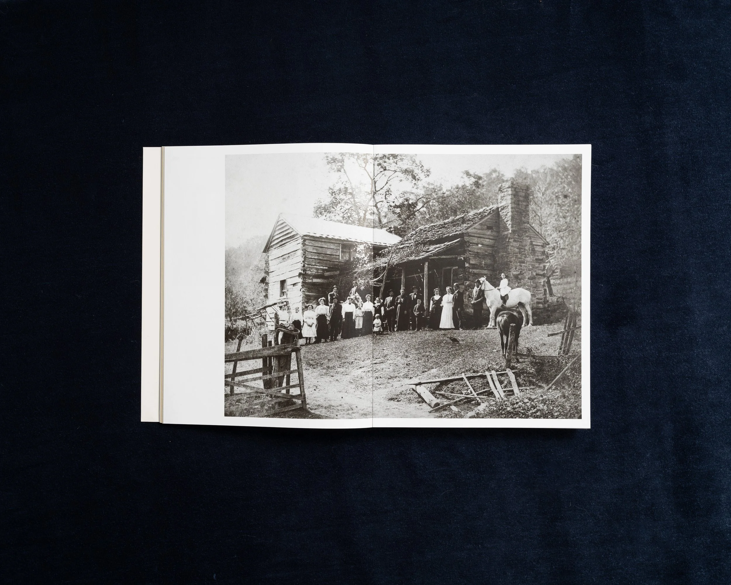 Archival photograph of a large family outside a wooden Appalachian home in Stacy Kranitz’s photobook