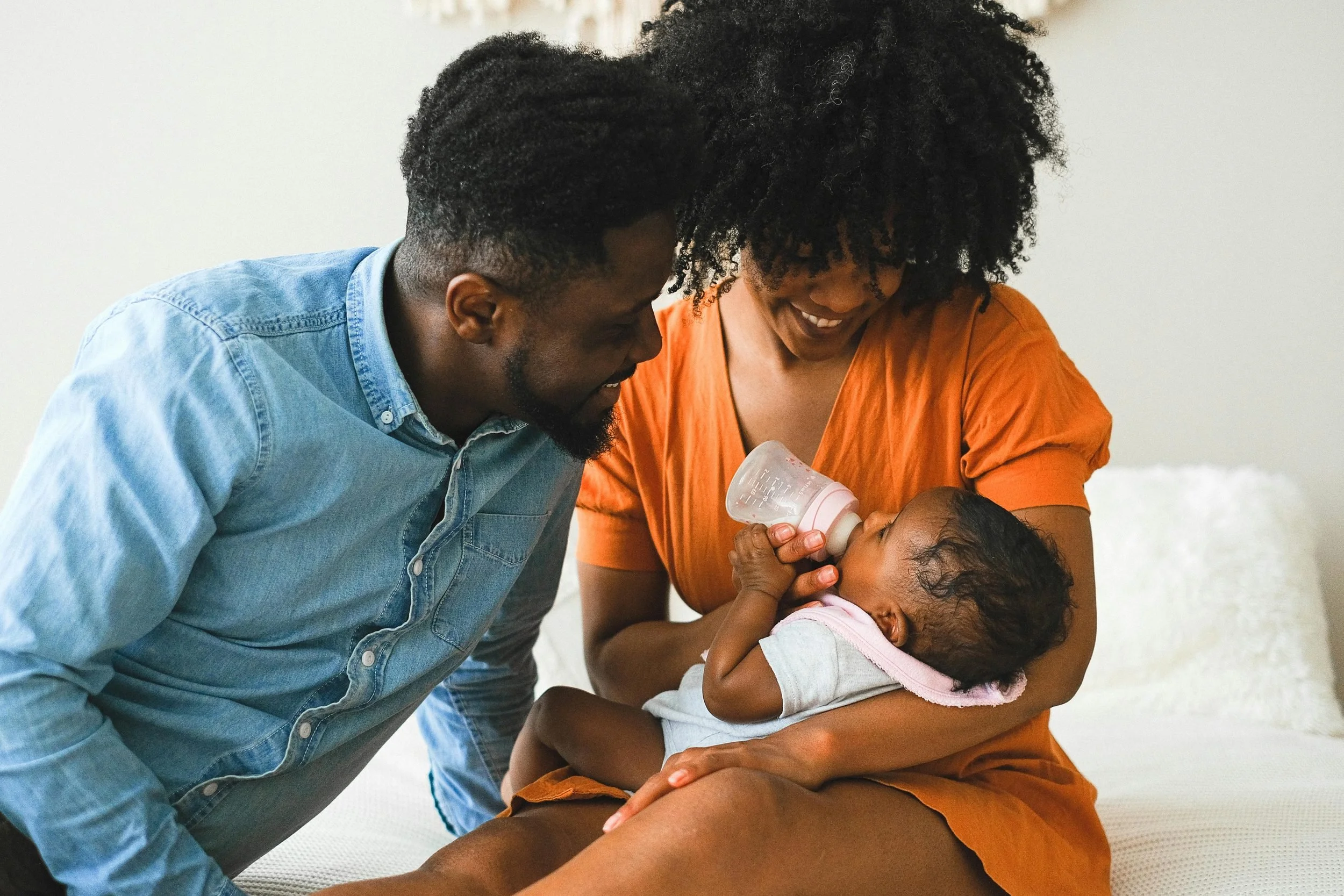 Parents holding and bottle-feeding their newborn