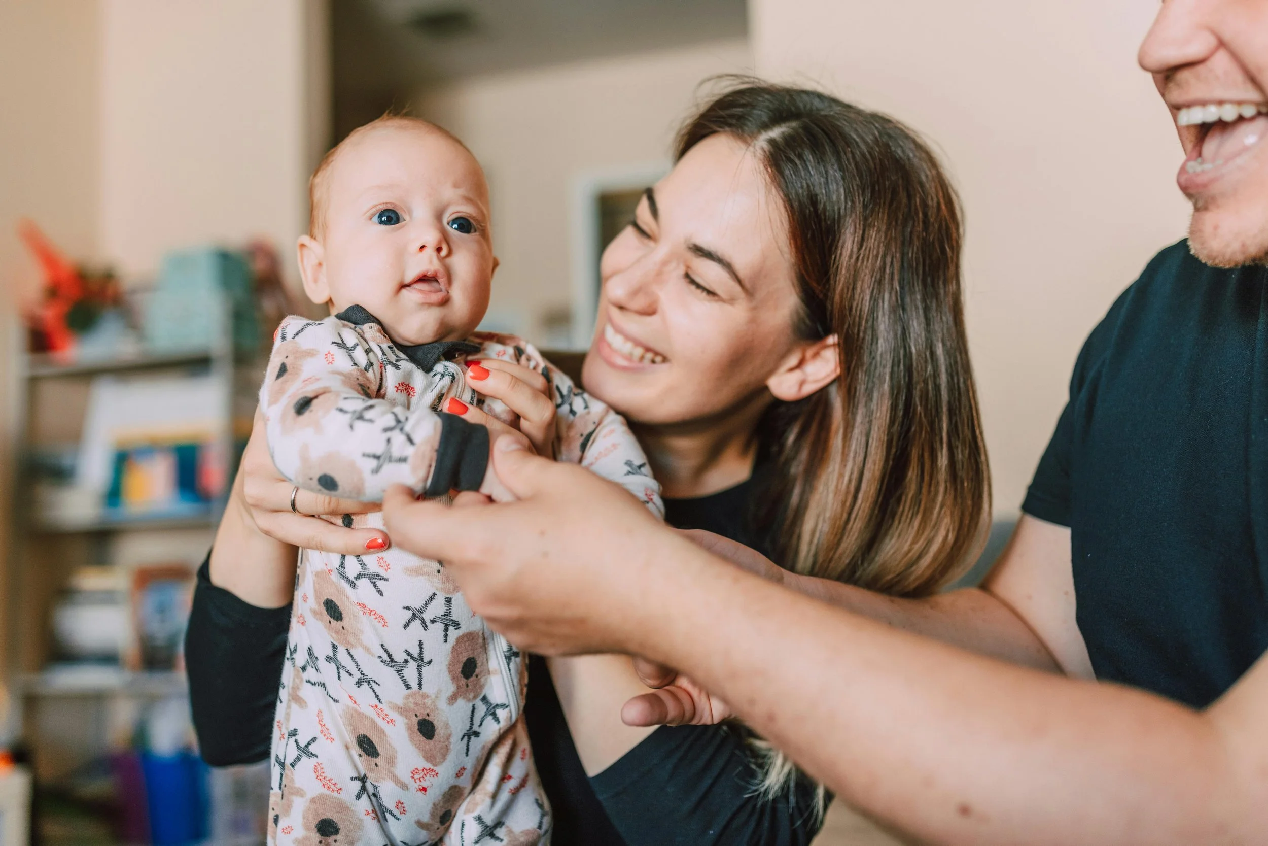 Two intended parents holding their baby indoors on their independent surrogacy journey
