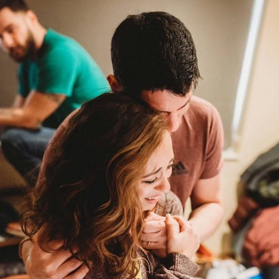 A woman and a man comfort each other with the woman crying and the man holding her close.