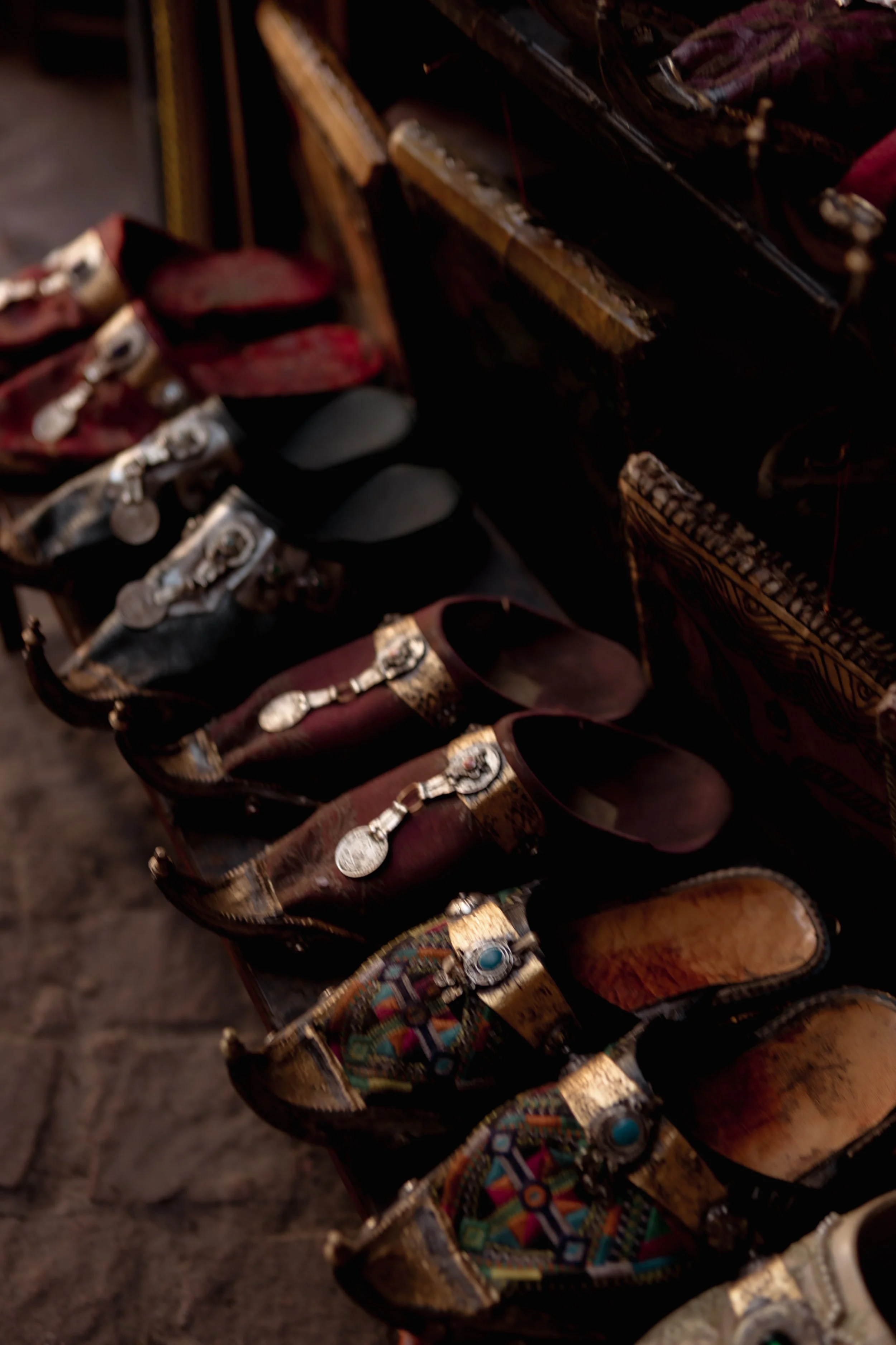 A row of colorful, decorated shoes with various patterns and embellishments, displayed on a dark surface.