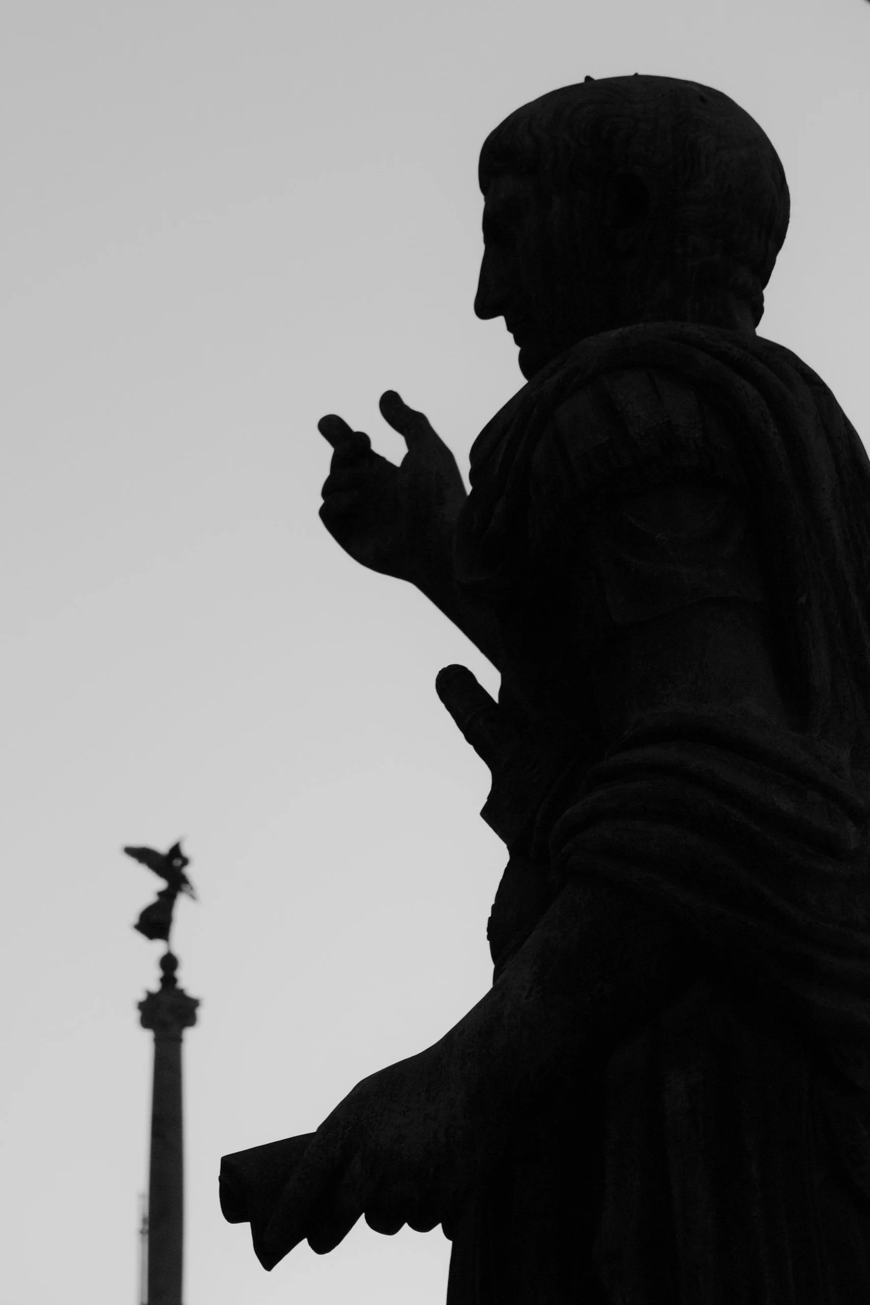 Silhouette of a person looking at their phone, with a monument and an eagle atop a column visible in the background, possibly in Washington D.C.