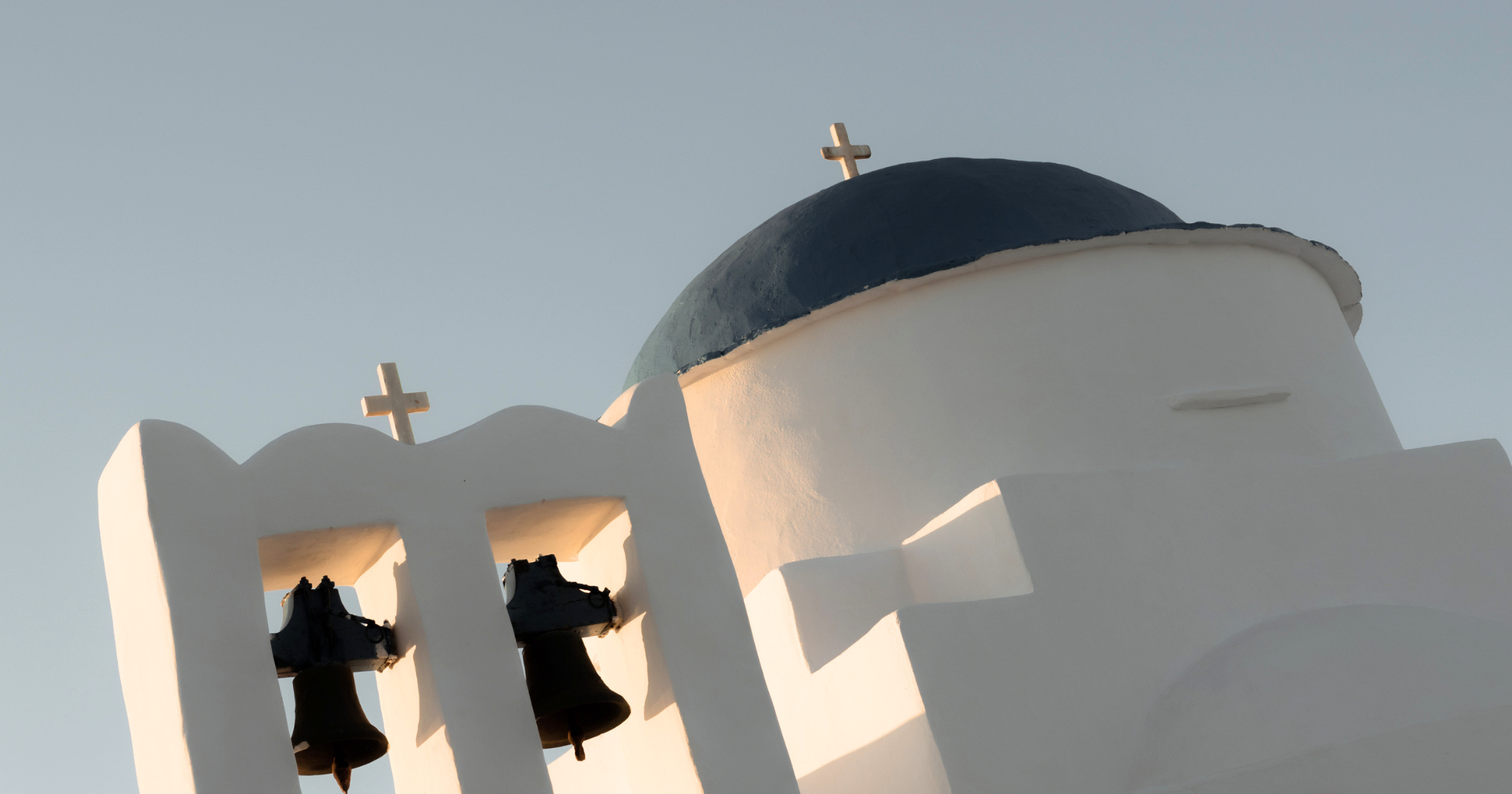 White church with blue domed roof and small crosses on top, capturing a sunny day with clear sky.