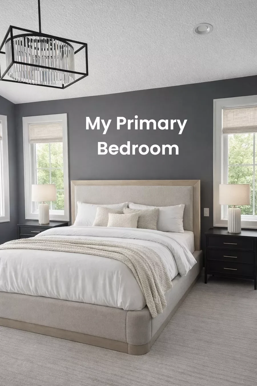 A modern primary bedroom with a gray accent wall, large windows, a beige upholstered bed with white and beige bedding, two black nightstands with white lamps, and a contemporary chandelier.