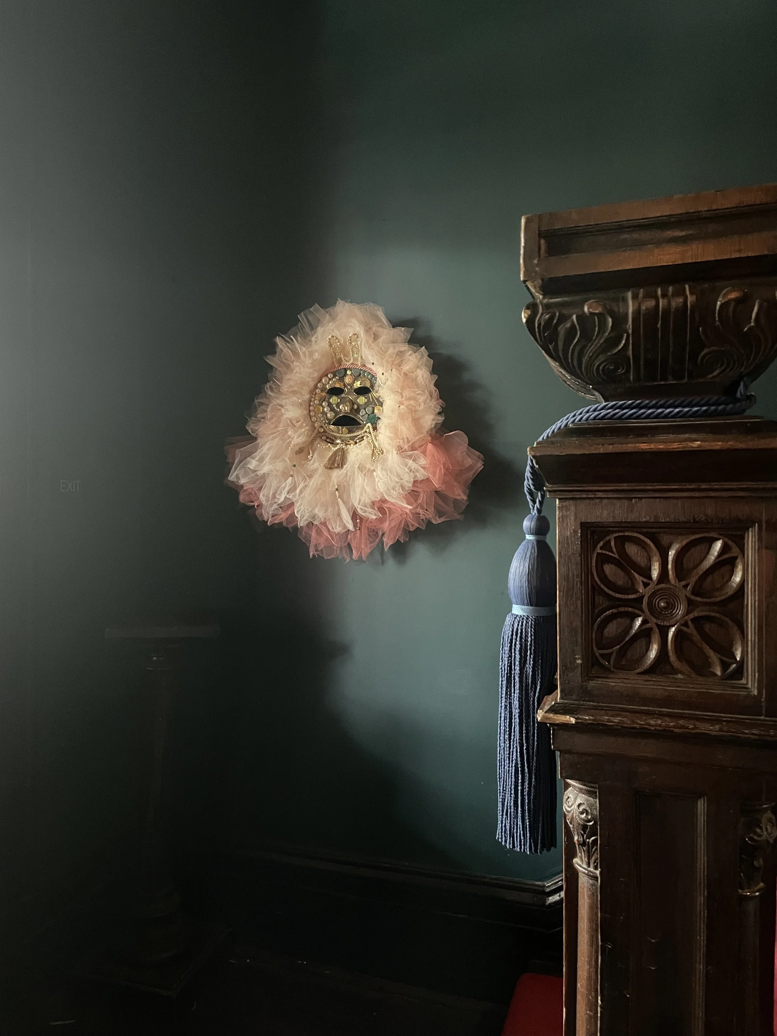 Small sculptural mask by Basqo Bim installed on a dark green interior wall at The Chloe Hotel.
