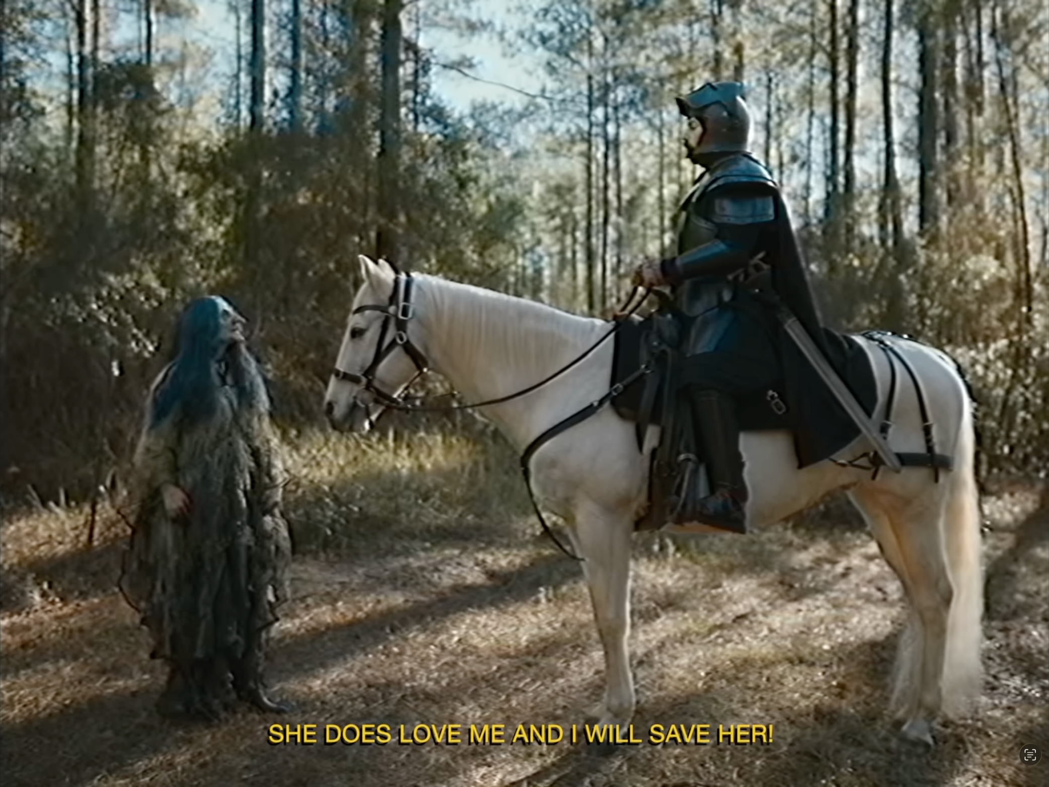 Film still from Duckboy – Excalibur showing a performer in Basqo Bim’s distressed green dress beside a white horse and armored rider.