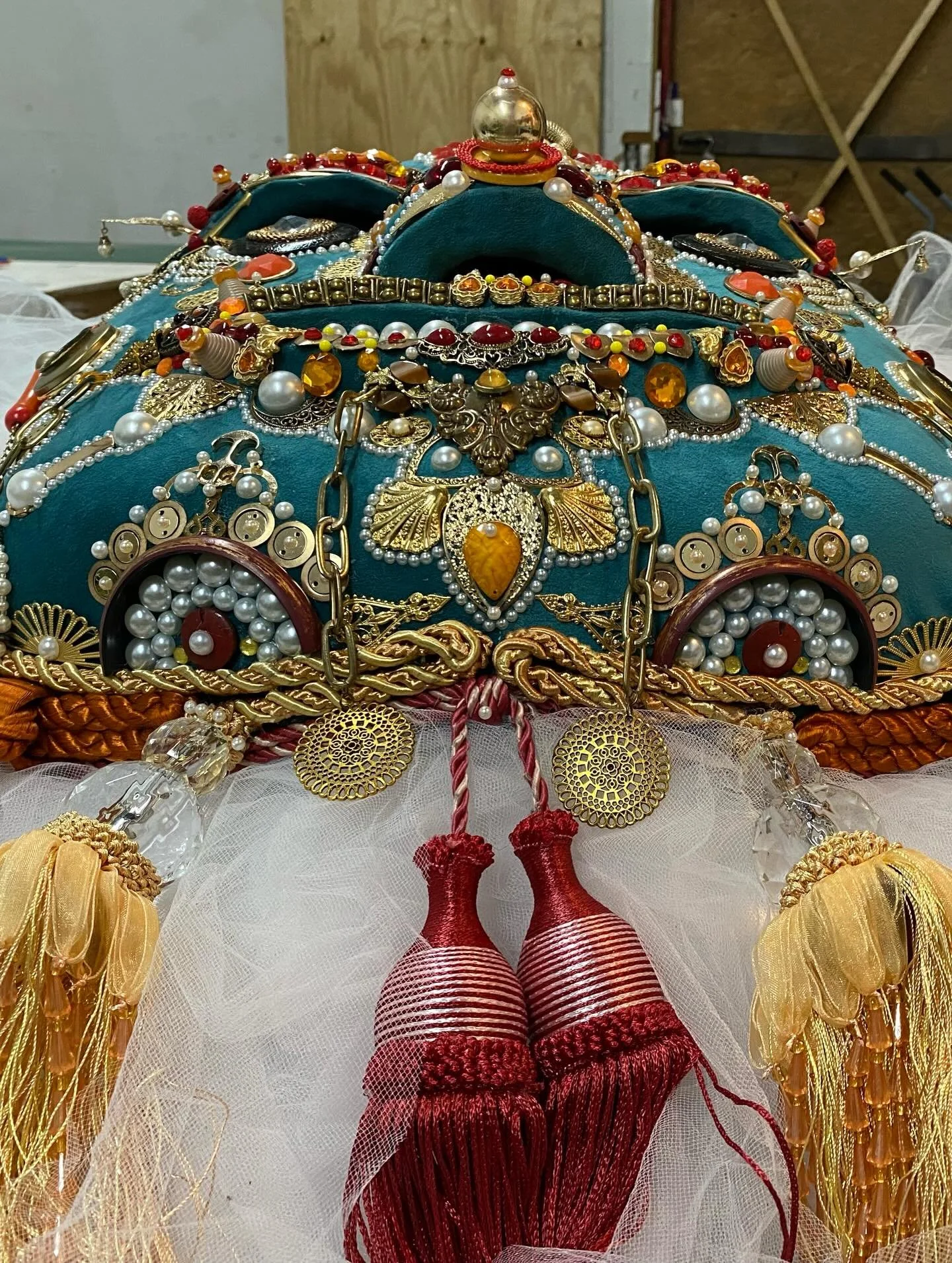 Top detail of Ajonjolí de Chartres by Basqo Bim showing pearl trim, red crest, gold ornament, and lower facial decoration.