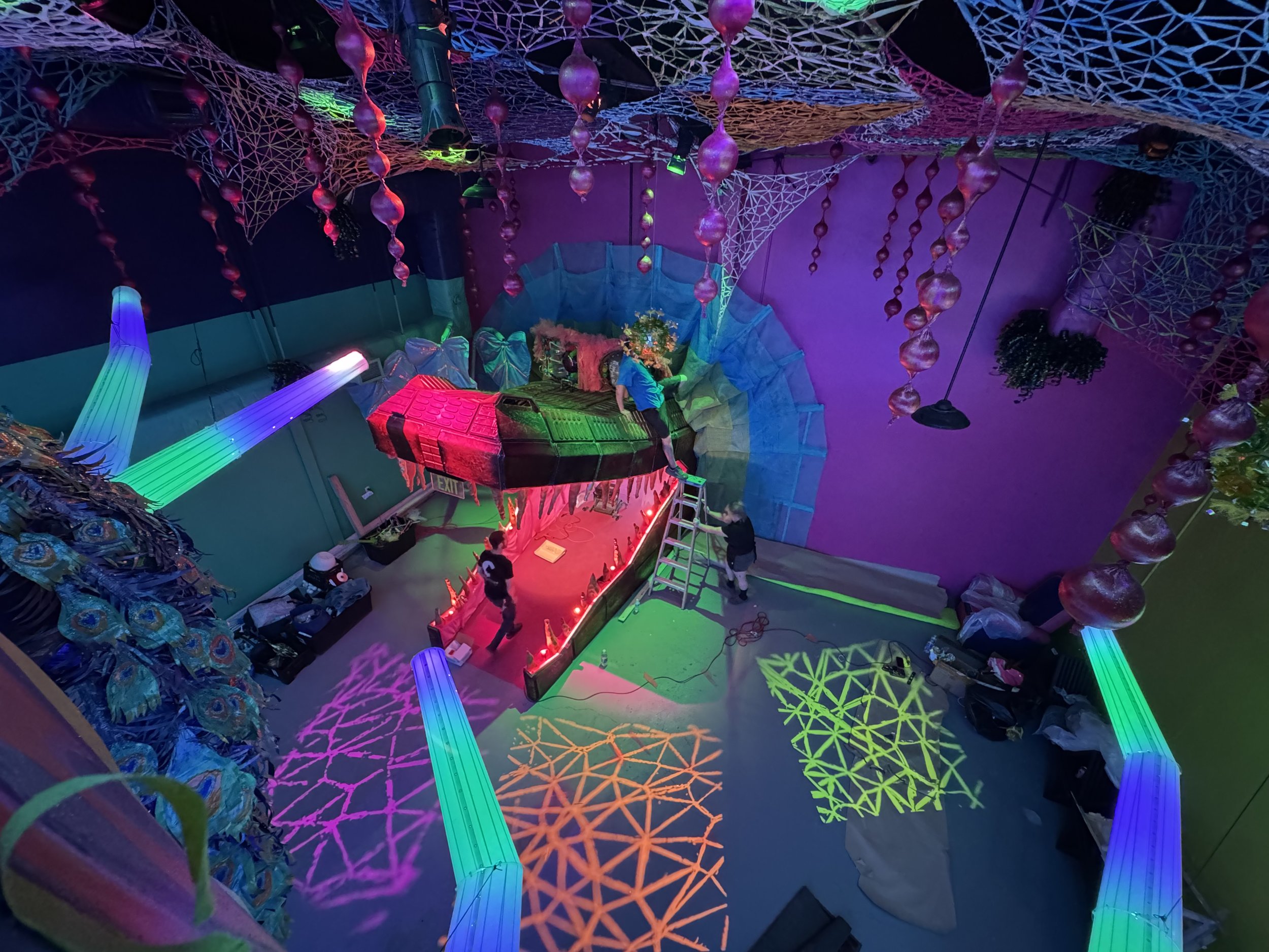 Overhead view of Tatán by Basqo Bim, an alligator-head installation with neon lighting, painted floor projections, and immersive interior environment.