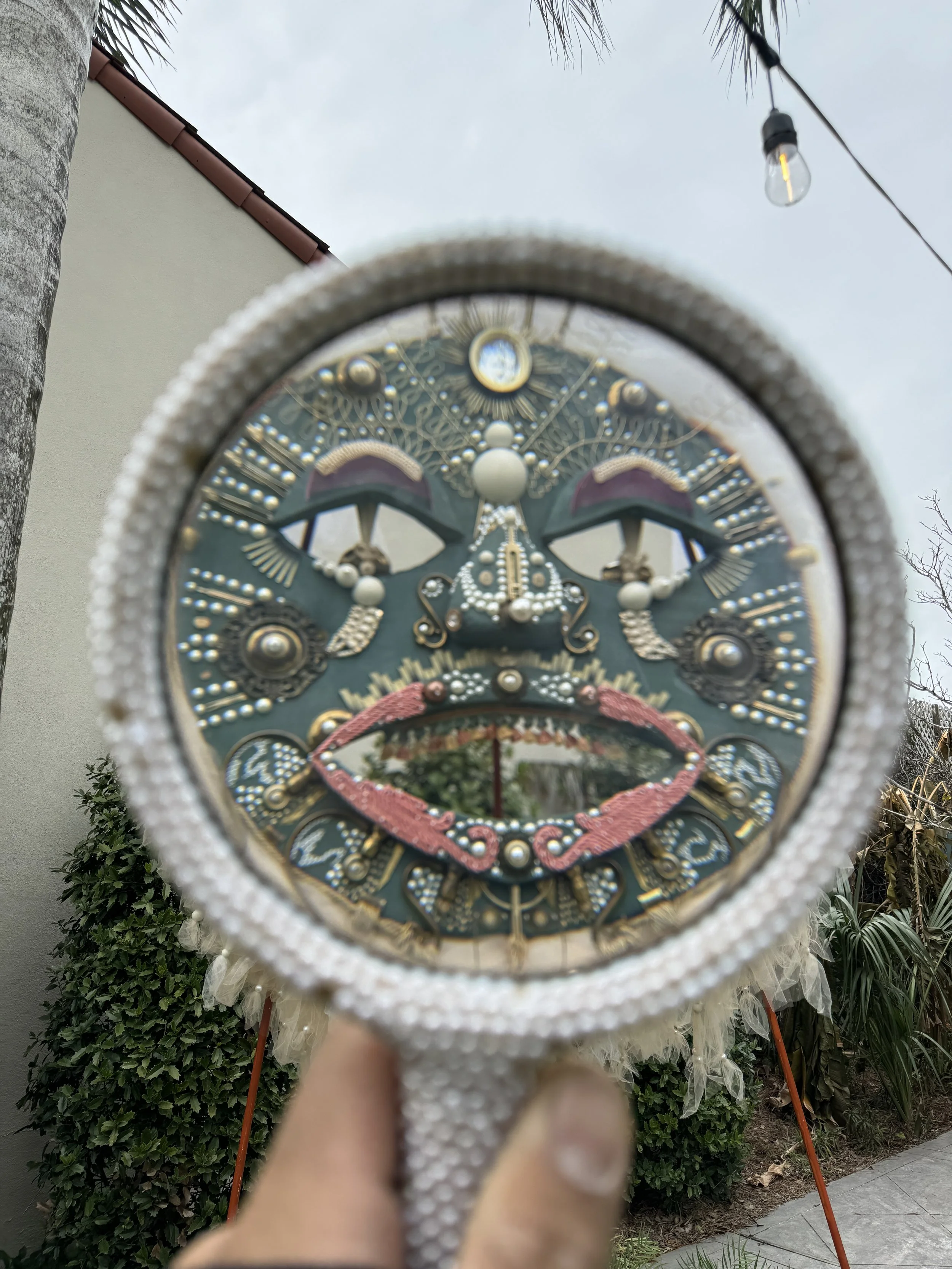 Mirror-framed view of a large sculptural mask installed outside at The Chloe Hotel.
