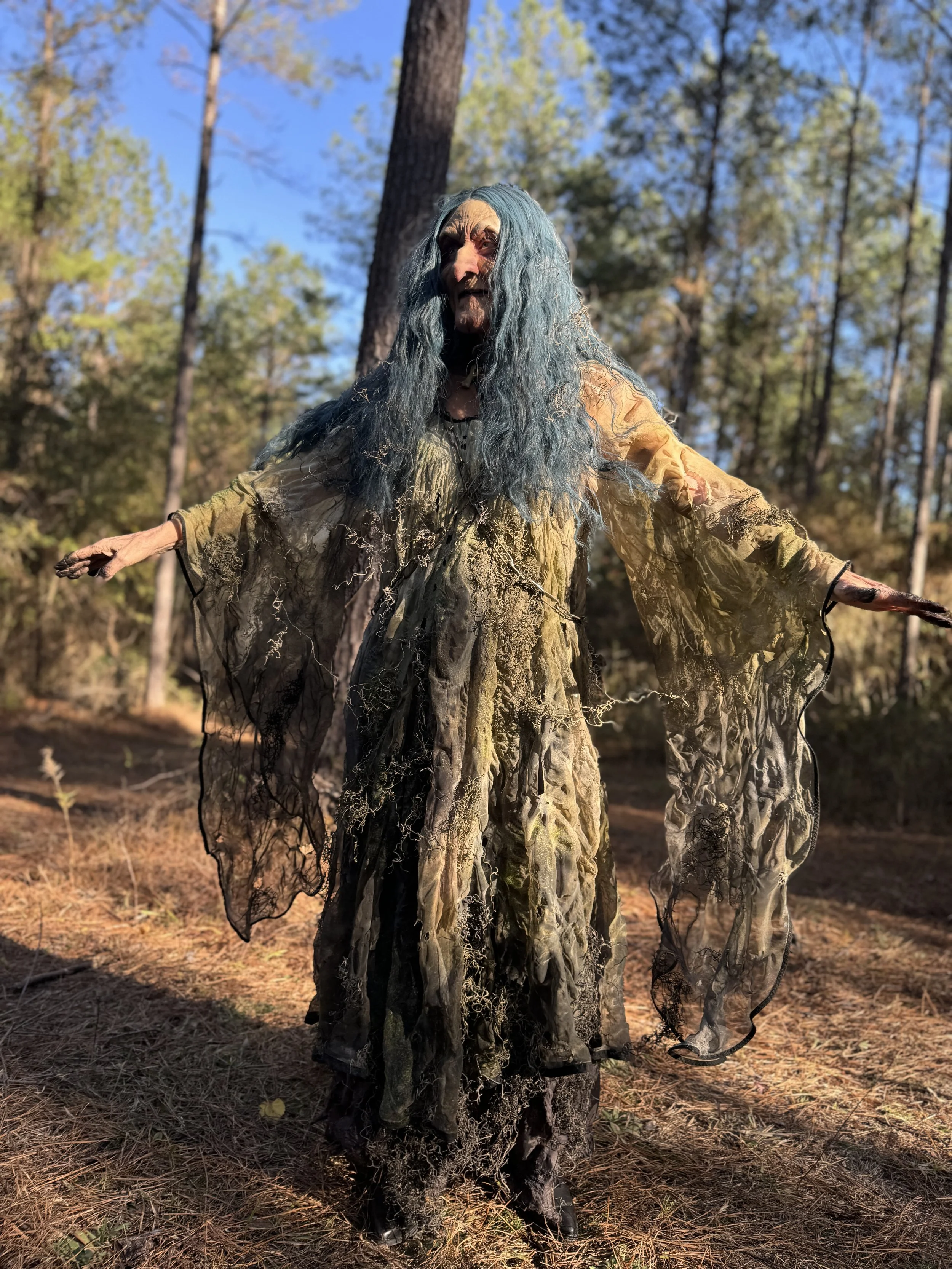 Performer wearing the distressed green dress created by Basqo Bim in a forest scene from Duckboy – Excalibur.