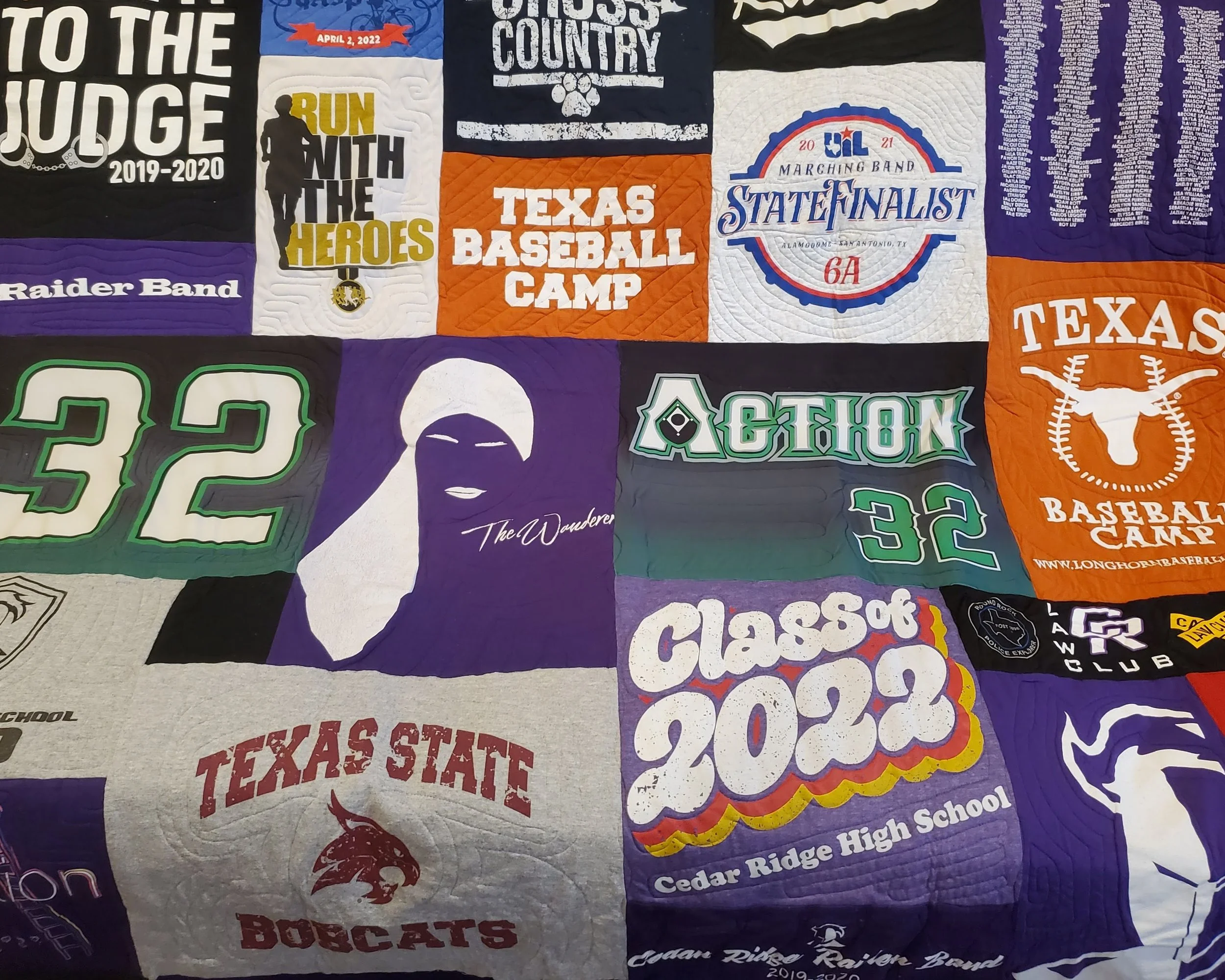 A quilt made of various school and sports team T-shirts, including Texas State Bulldogs, Cedar Ridge High School, and Texas Baseball Camp, featuring logos, numbers, and text in different colors.