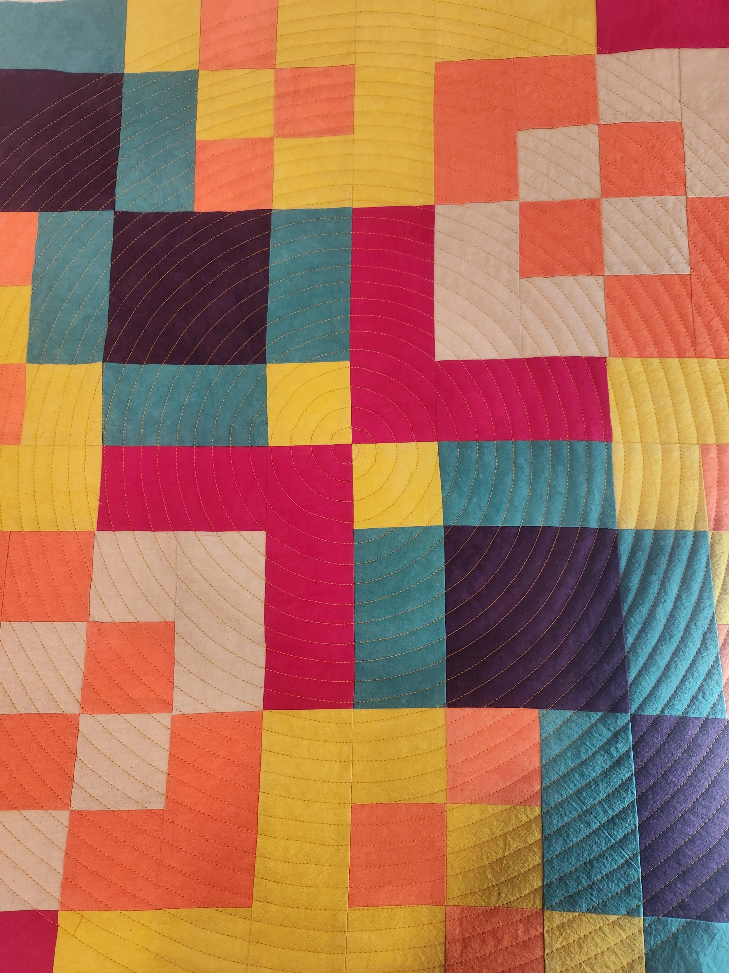 Close-up of a colorful patchwork quilt with concentric circular stitching patterns.