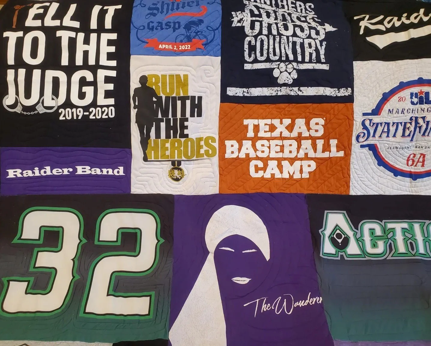 A quilt made up of various fabric patches, featuring sports team logos, event announcements, motivational quotes, and artistic designs.