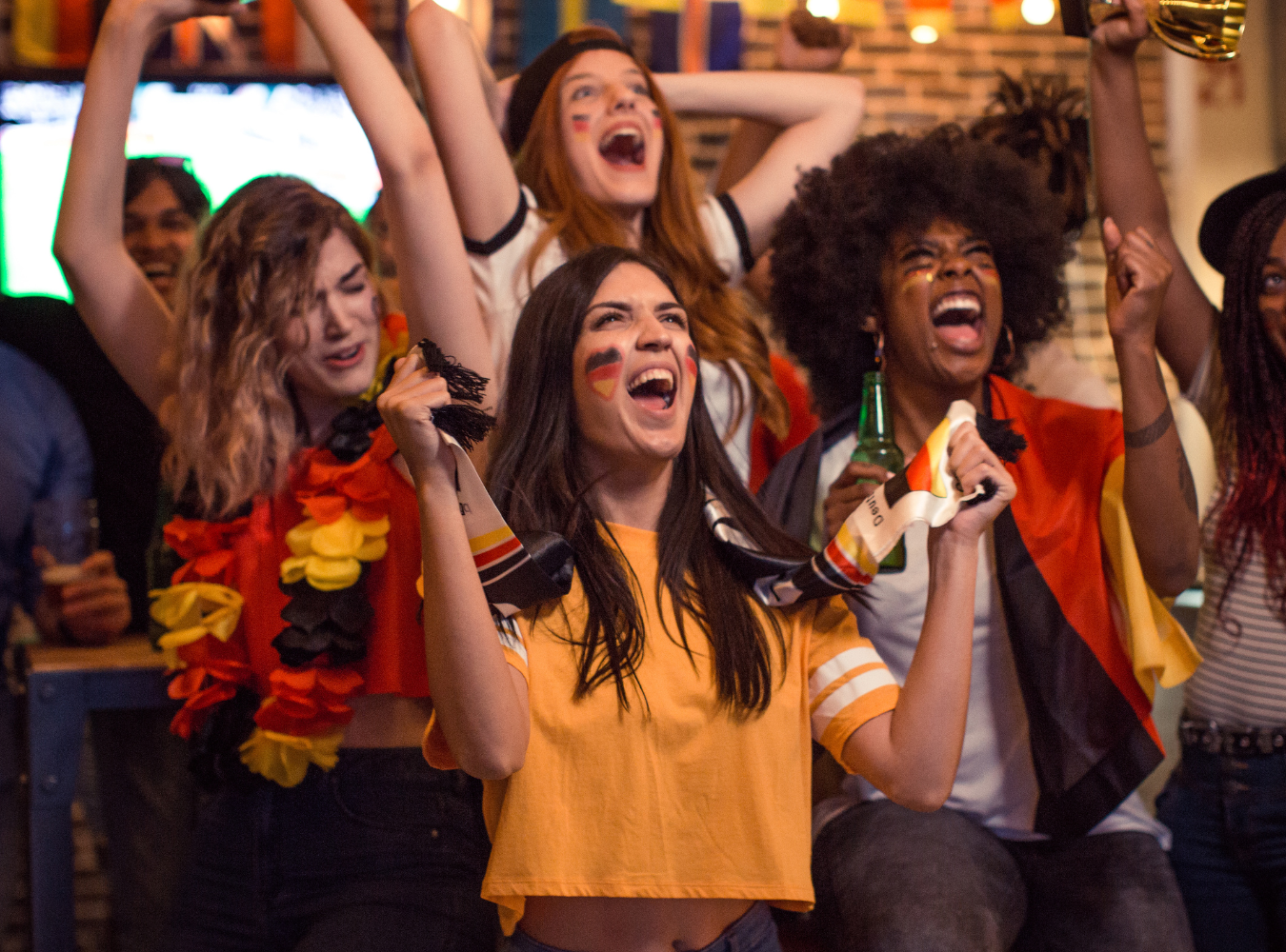Germany national team fans draped in national colors celebrating a goal at a premier soccer destination in the Grand Central Terminal corridor, anchored in a high-capacity Manhattan fan zone.
